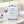 A white MYCHWAY facial treatment machine with two bottles labeled A and B, a clear collection cup, and a handheld applicator, displayed on a marble bathroom counter with folded towels nearby.