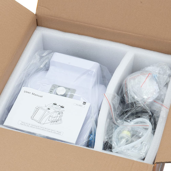 Open cardboard shipping box containing a white electronic device wrapped in plastic, a printed user manual, and accessories in clear bags on white foam insert.