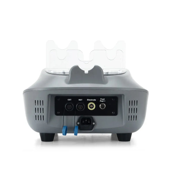 The rear view of a gray electronic beauty device, likely an IPL skin treatment unit, featuring a black control panel with input/output ports, power cord, and two blue grounding leads, with two clear protective covers on top.